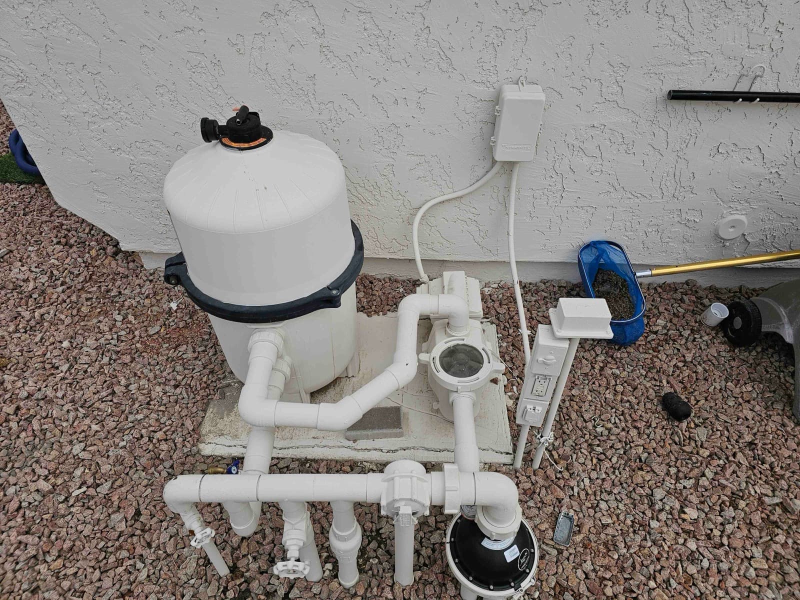 Example: a pool equipment pad photographed from the side, the filter tank showing its full height from lid to base with the pump and pipework beside it.